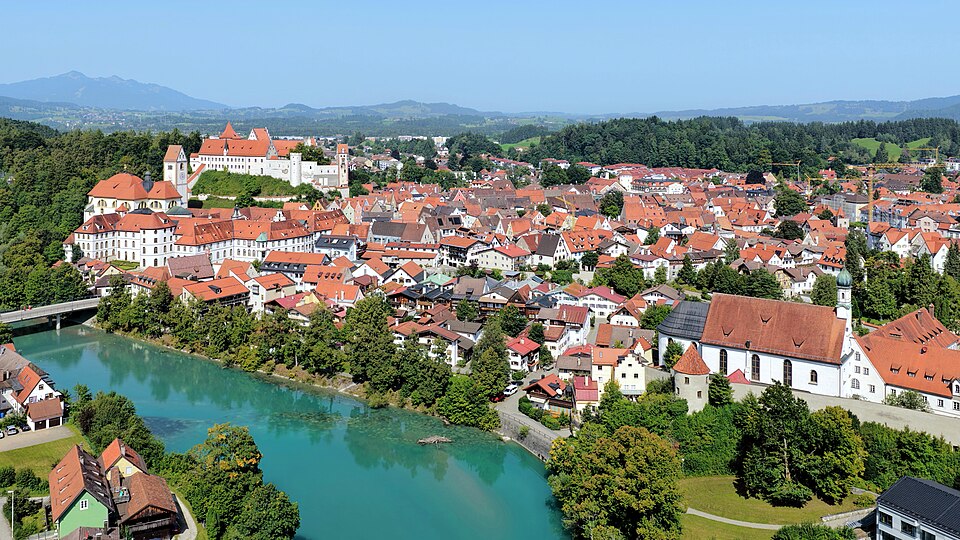 The rooftops of Füssen's old town beside the turquoise Lech, with the Hohes Schloss on its hill.